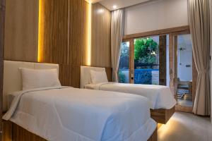 a bedroom with two beds and a window at Villa D'Ling in Tianyar +11 photos