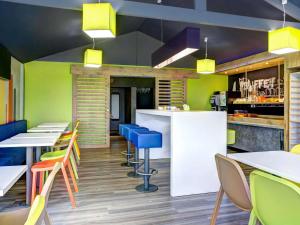 a restaurant with colorful chairs and tables and a bar at ibis budget Caen Hérouville in Hérouville-Saint-Clair