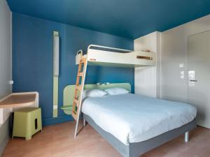 a bedroom with a bunk bed with a blue wall at ibis budget Caen Hérouville in Hérouville-Saint-Clair