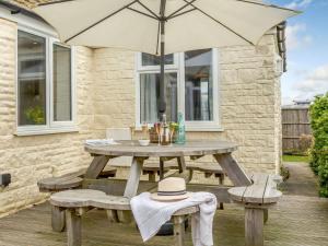 a wooden picnic table with benches and an umbrella at 3 Bed in West Bay DC117 in West Bay
