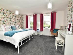 a bedroom with a bed with red curtains and a desk at 4 Bed in Gosforth 85807 in Gosforth