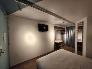 a bedroom with a bed and a television on the wall at ibis budget Chambourcy Saint Germain in Chambourcy