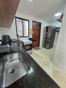 a kitchen with a sink and a stainless steel refrigerator at Villas do Rio 02 in Pôrto de Pedras