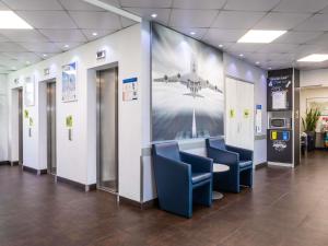 a lobby with chairs and a large picture of an airplane at ibis budget Roissy CDG Paris Nord 2 in Roissy-en-France