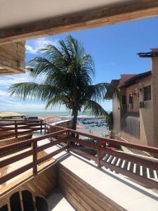 a view of the beach from a balcony with a palm tree at Pipa's Bay Apt 104 - PÉ NA AREIA in Pipa