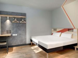 a bedroom with a white bed and a desk at Hotel Ibis Budget Montpellier Centre Millenaire - in Montpellier
