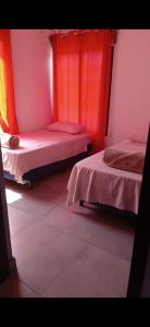 two beds in a room with red curtains at Villa Coral Gables Casa in Puerto Jiménez