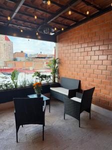 un patio con sillas, un banco y una pared de ladrillo en El Suburbio - Aldama, en Morelia