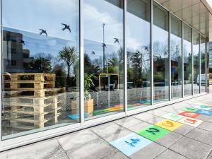 a glass facade of a building with birds in the window at Hotel ibis Budget Porto Gaia in Vila Nova de Gaia