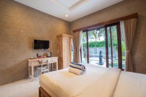 a bedroom with a bed and a desk and a television at Grita Apsari Guest House in Tegalalang