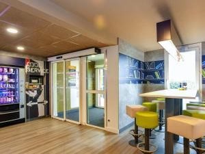 a restaurant with a bar with yellow chairs at ibis budget Coutances in Coutances
