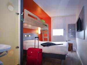 a hotel room with a bed and a red suitcase at ibis budget Coutances in Coutances +64 photos