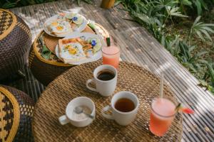 a table with a plate of food and two cups of coffee at Nirvana Bamboo House Sidemen - The Aesthetic Stay in Sidemen
