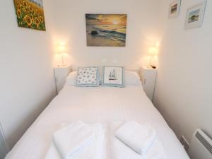 a small bedroom with a white bed with two pillows at 51 Longstone Park in Chathill