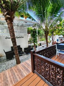 a wooden deck with chairs and palm trees on it at บุญเมืองน่าน in Nan +34 photos
