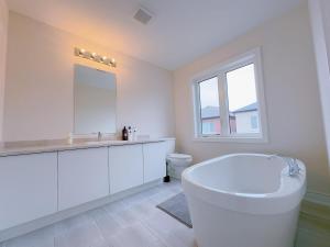 a white bathroom with a tub and a sink at Vantage stay Modern 4BR townhouse pickering in Pickering