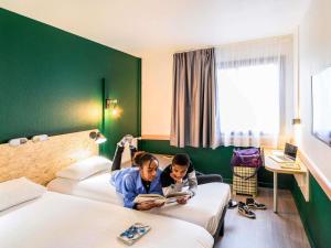 zwei Personen liegen auf Betten in einem Hotelzimmer in der Unterkunft Greet Hotel Evreux Centre - Route de Normandie by Accor in Évreux