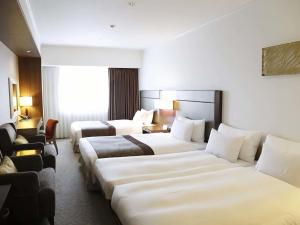a hotel room with three beds and a chair at Ibis Styles Sapporo in Sapporo +65 photos