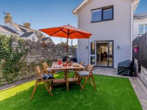 a table and chairs with an umbrella on a lawn at 3 Bed in Porthcawl 85193 in Newton
