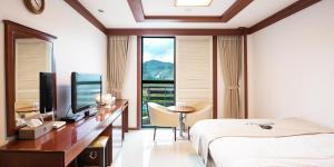 a hotel room with a bed and a desk with a television at Benikea Hotel Cheong Do Hot Spring in Cheongdo