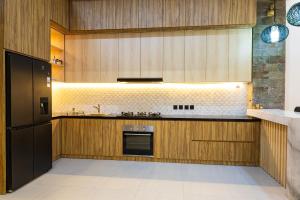 a kitchen with wooden cabinets and a black refrigerator at Villa D'Ling in Tianyar