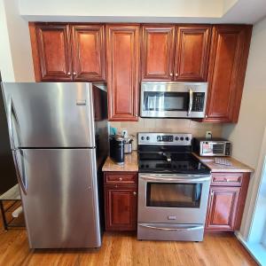 a kitchen with wooden cabinets and stainless steel appliances at Spacious Apt in Fairview NJ Easy Commute to NYC with parking in Fairview