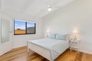Un dormitorio blanco con una cama y una ventana. en 9 Callow Place, en Bermagui
