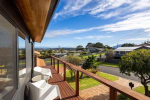 balcón con sillas blancas y vistas a la calle en 9 Callow Place, en Bermagui