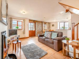a living room with a leather couch and a television at 4 Bed in Llandovery 82440 in Llanfair-ar-y-bryn