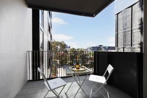 a balcony with two chairs and a table on a balcony at Walk to Everything! Brand New Box Hill 1-Bed Gem in Box Hill