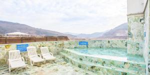 a swimming pool with chairs and mountains in the background at Benikea Hotel Cheong Do Hot Spring in Cheongdo