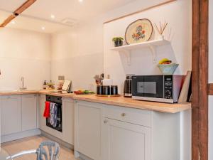 une cuisine avec des placards blancs et un four micro-ondes sur un comptoir dans l'établissement 1 Bed in Sherborne 94306, à Chetnole