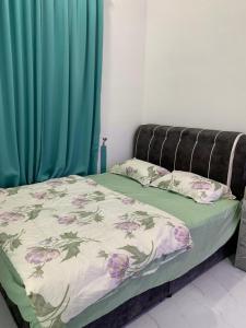 a bed with a floral comforter and two pillows at Damai Homestay, Kg Bukit, Terengganu in Kuala Terengganu