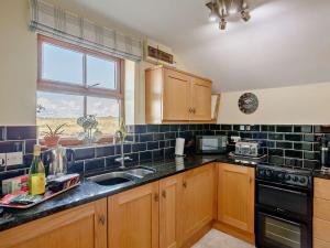 a kitchen with wooden cabinets and a sink and a window at 1 bed in Stamford Bridge 92093 in High Catton +8 photos