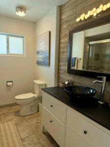 a bathroom with a sink and a toilet and a mirror at Endless Summer, Pool, Theatre, Boat Parking, Walk to London Bridge! in Lake Havasu City