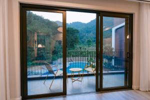 a room with sliding glass doors and a balcony with a table and chairs at Soc Village Wellness & Retreat in Sóc Sơn