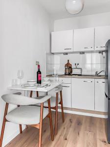a white kitchen with a table with a bottle of wine at Chic City Apartment, 1BR for 2, Elegant Comfort, City Center in Wuppertal +27 photos