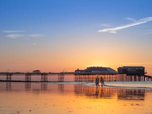 a person walking on the beach with a pier in the background at 3 Bed in Northrepps 88327 in Northrepps