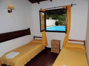 ein Zimmer mit zwei Betten und einem Fenster mit Blick auf den Pool in der Unterkunft Chill hotel in Villa Gesell