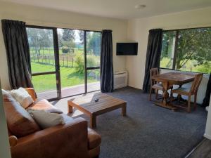 een woonkamer met een bank en een tafel bij The Barnyard Cottage in Otakiri