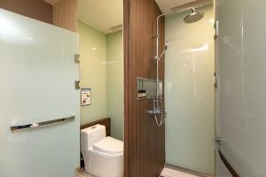 a bathroom with a toilet and a glass shower door at Confucius Temple Yisu Hotel in Gaoqiao