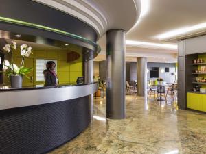 Una mujer parada detrás del mostrador de un restaurante. en Adagio Original Thoiry Genève, en Thoiry