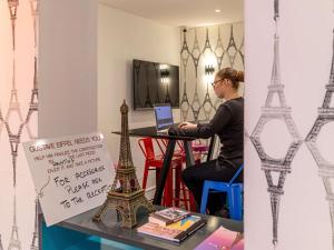 a woman sitting at a table with a laptop at ibis Styles Paris Eiffel Cambronne in Paris