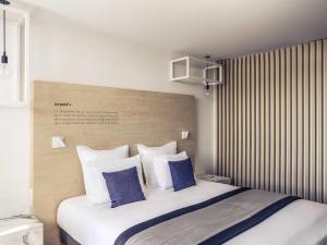 a bedroom with a large white bed with blue pillows at Mercure Nancy Centre Gare in Nancy