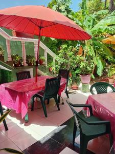 a red table with chairs and a red umbrella at Habitación Matrimonial - Parejas - Frente al mar in Estación El Salto