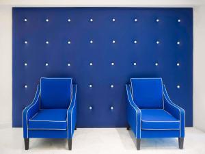 two blue chairs in front of a blue wall at Hotel Mercure Jardines de Albia in Bilbao