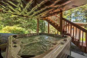 a hot tub on the deck of a house at Secluded Log Cabin with Hot Tub Fire Pit Game Room in Newfoundland