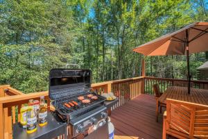 a grill on a deck with a table and an umbrella at Secluded Log Cabin with Hot Tub Fire Pit Game Room in Newfoundland