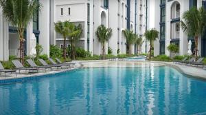 una piscina di fronte a un edificio con palme di Title HALO 1 - Modern 1BR Pool View Walk to Nai Yang Beach a Nai Yang Beach