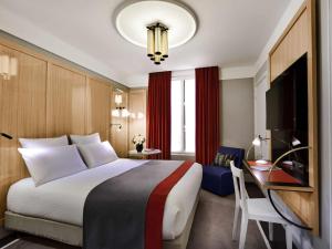 a hotel room with a large bed and a desk at l'Echiquier Opéra Hotel Paris - MGallery Collection in Paris